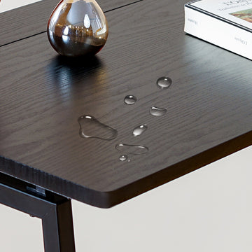 Dark wooden table with water droplet designs and decorative items on a light background