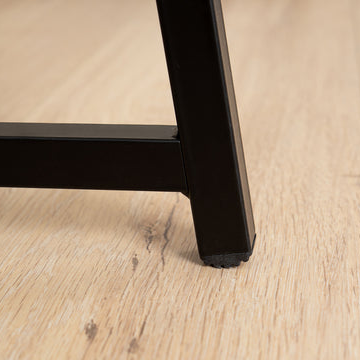 Black metal leg of a piece of furniture on a wooden floor