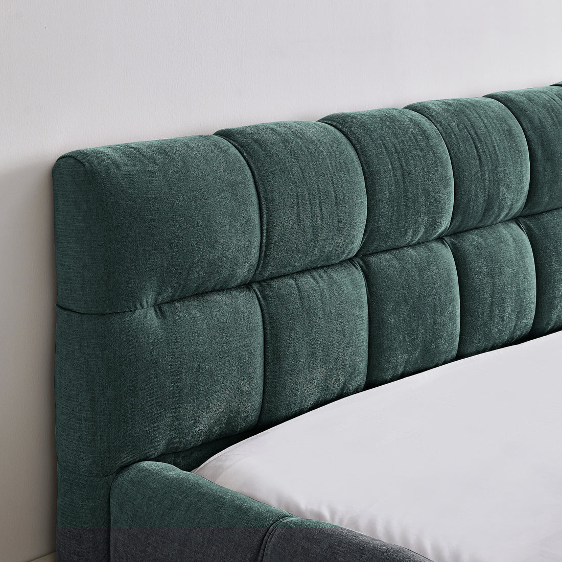 Green upholstered headboard on a bed with white bedding.