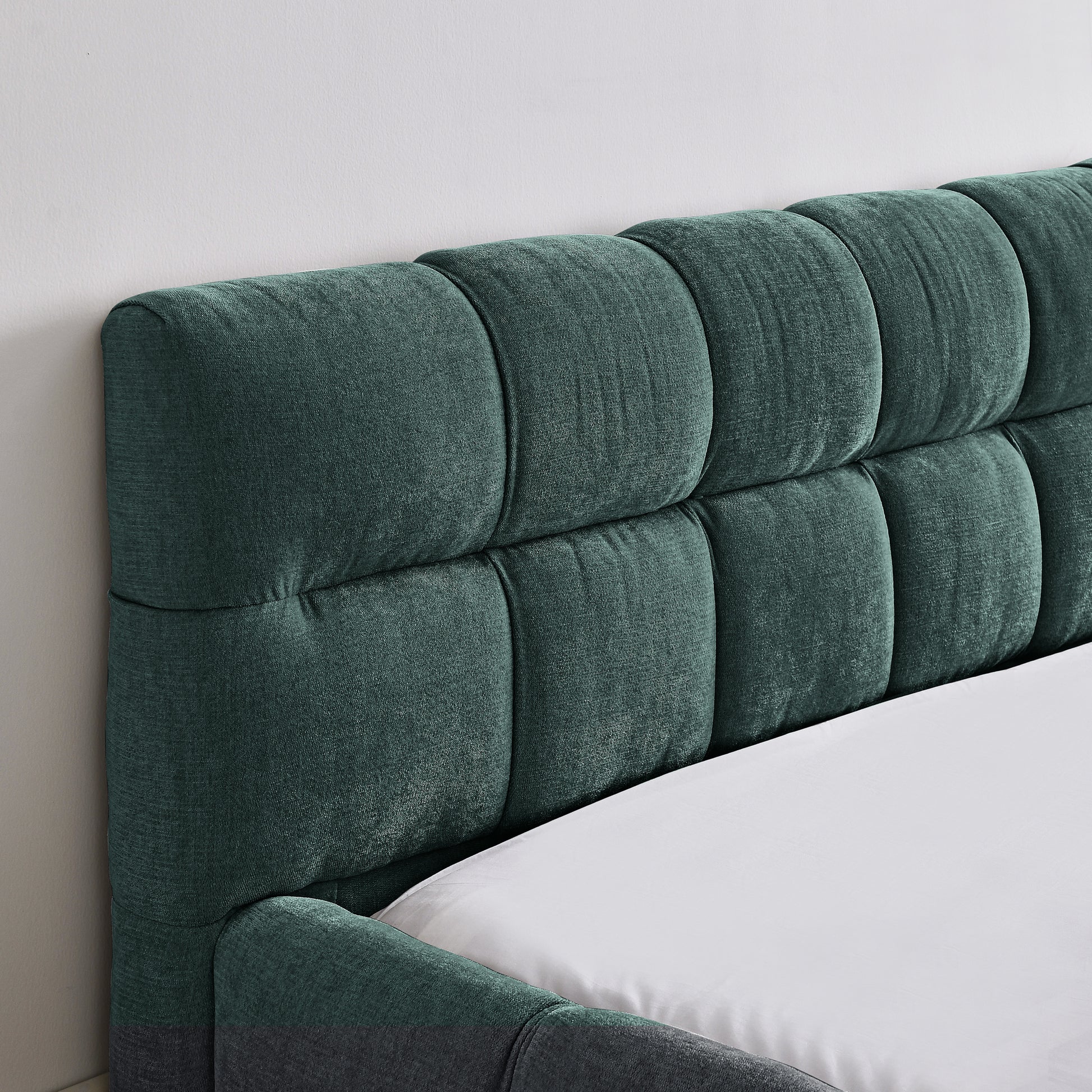 Green upholstered headboard on a bed with white bedding.