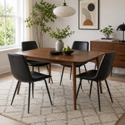 Amalfi black faux leather dining chairs with black metal legs around a round wood dining table