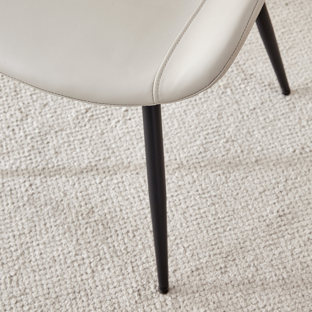 Amalfi light grey dining chair close-up of the slim black metal leg beneath the upholstered seat