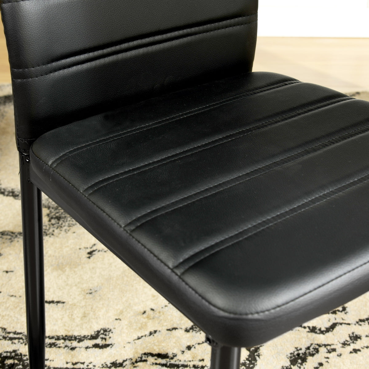 Ann black faux leather dining chair showing padded seat detail