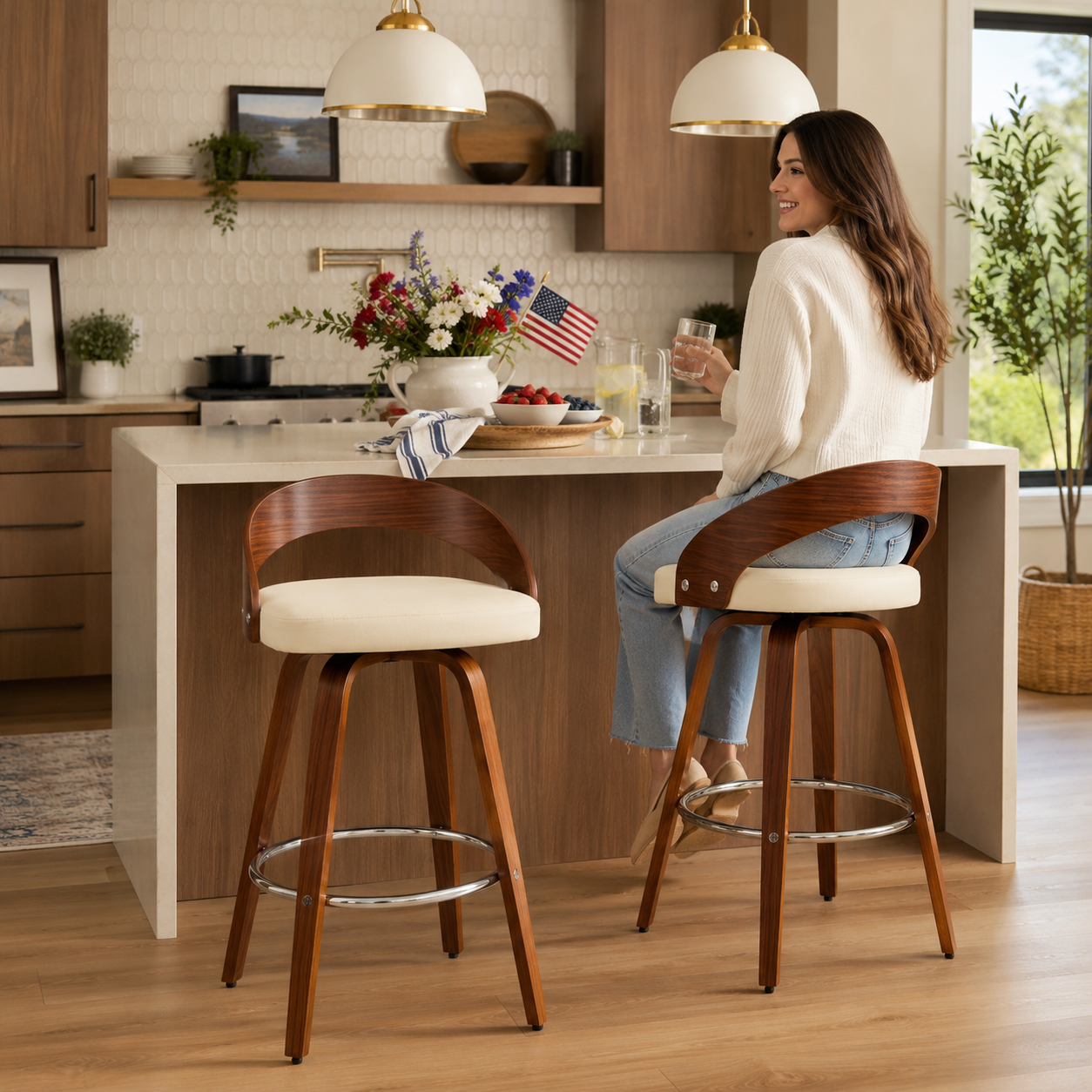 Woman sitting at a kitchen island with wooden bar stools, smiling.
