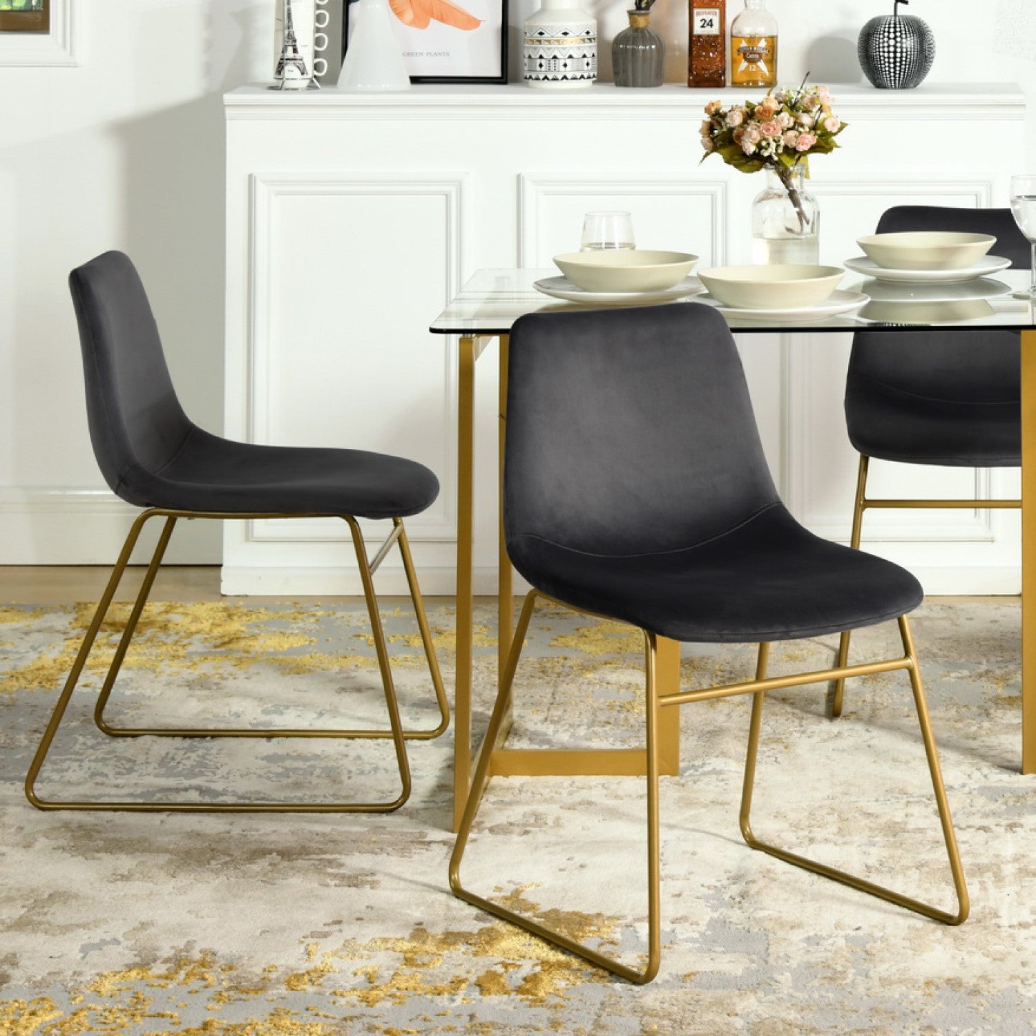 Batassel black velvet dining chairs with gold metal base around a round pedestal dining table