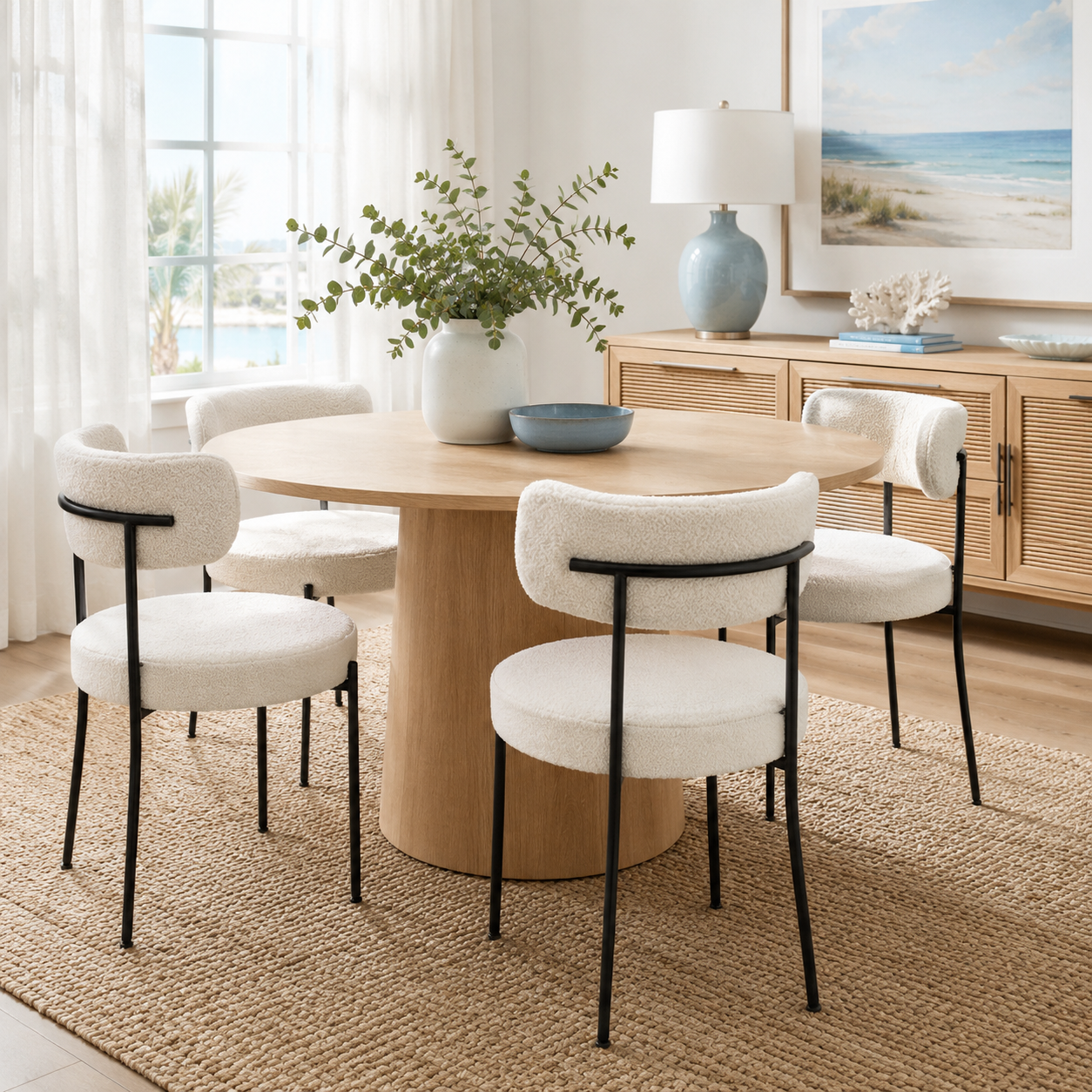 Bled white dining chairs with curved backs beside a round dining table in a sunlit room