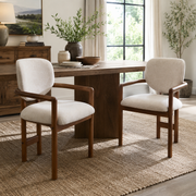 Bracciano brown upholstered dining armchairs beside a round wood dining table in a warm dining room