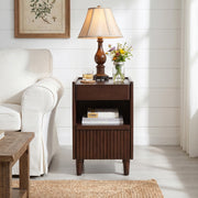 Brennor walnut nightstand showing angled front view beside a sofa