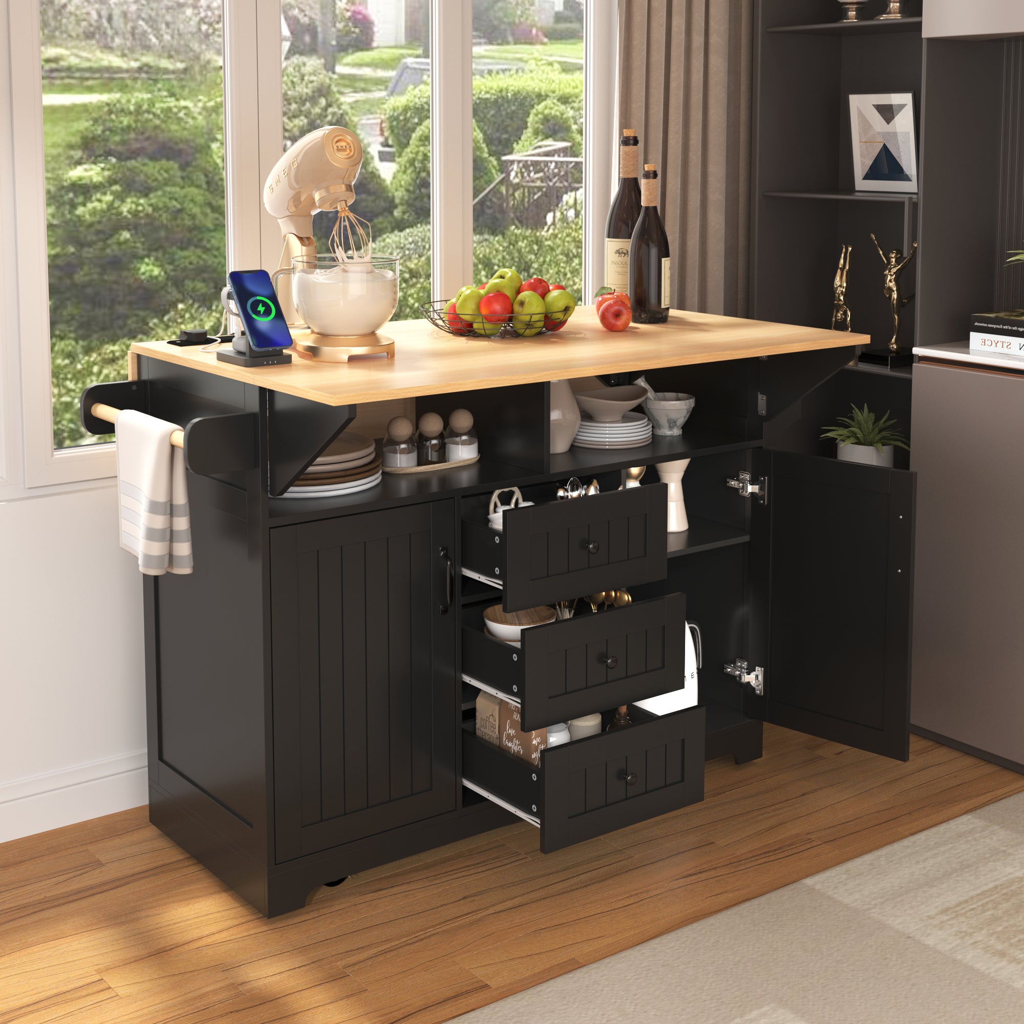 Lifestyle image of the black BRYNNA rolling kitchen island with open drawers and cabinet storage, drop leaf countertop, towel rack, spice shelf, and multifunctional kitchen organization design