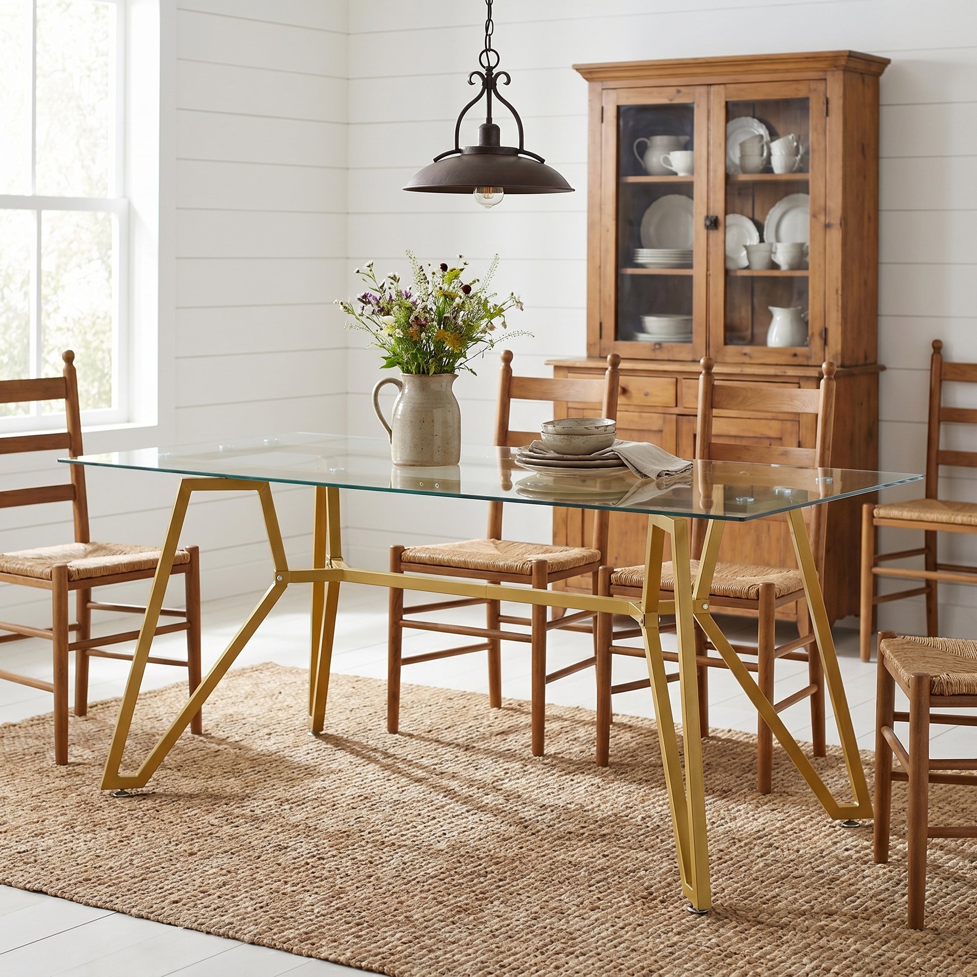 Caspian gold dining table showing a glass dining table with wood chairs beside open shelving