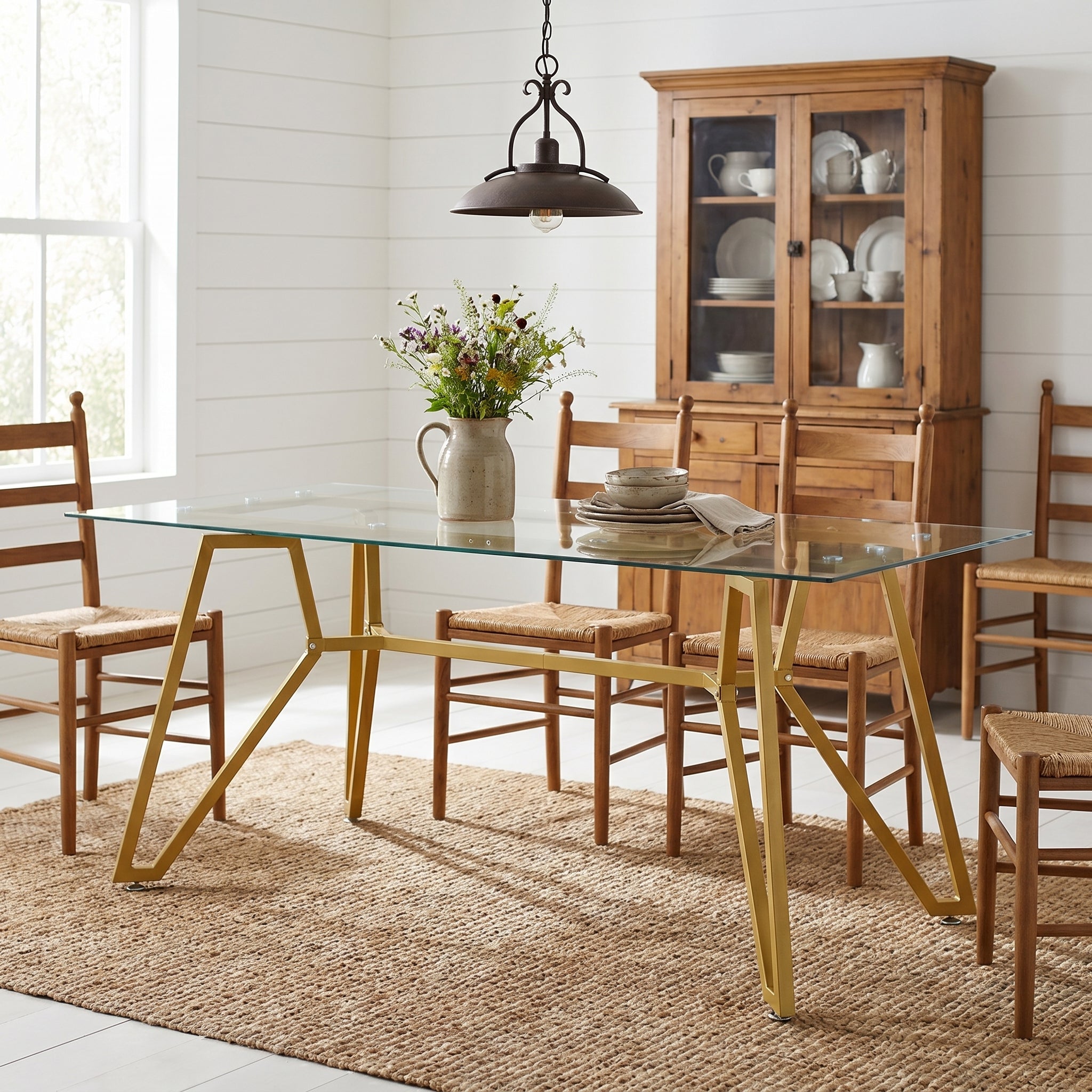 Caspian gold dining table showing a glass dining table with wood chairs beside open shelving