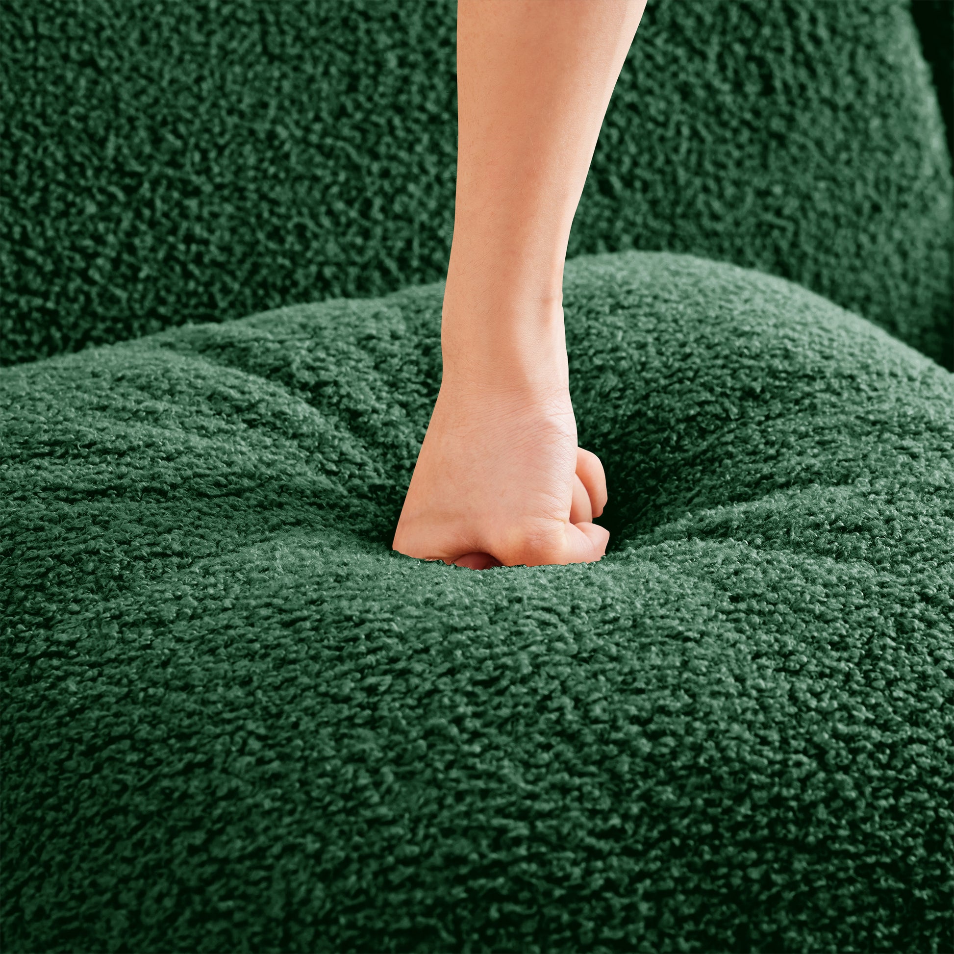 Hand pressing Chico green teddy fabric cushion showing soft seating comfort detail