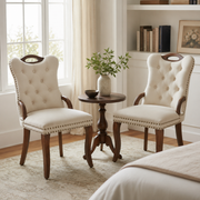 Elbe beige dining chairs showing a pair beside a round accent table in a bright room with tall windows