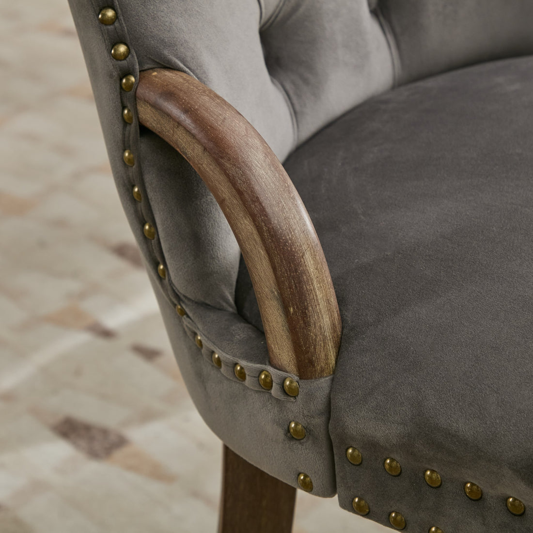 Elbe gray dining chair showing curved wood accent and antique brass nailhead trim detail