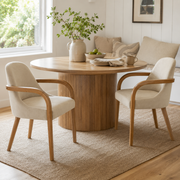 Geneva khaki upholstered dining chairs beside a round wood dining table in a bright dining room