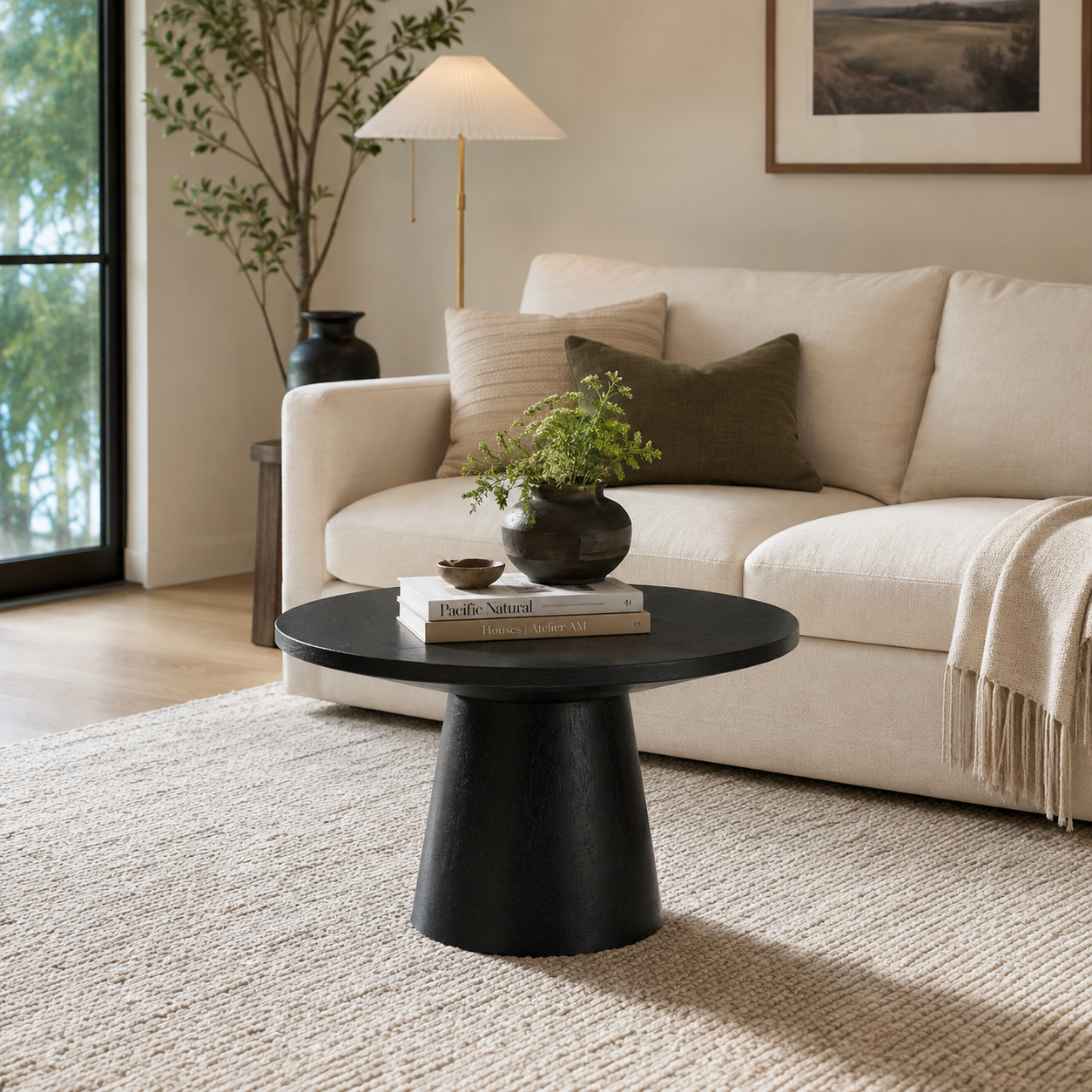Genoa black round coffee table with pedestal base in a bright living room with a cream sofa