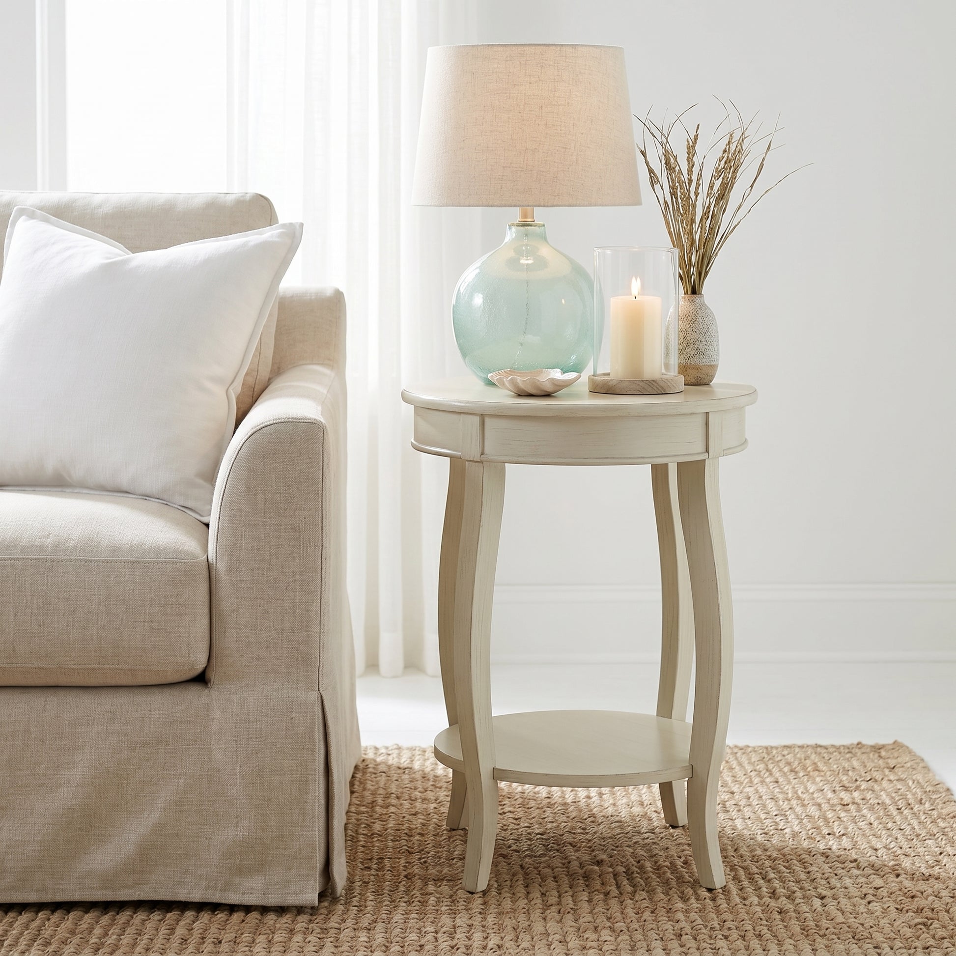 Gila white side table showing a compact round table with lamp and decor beside a sofa