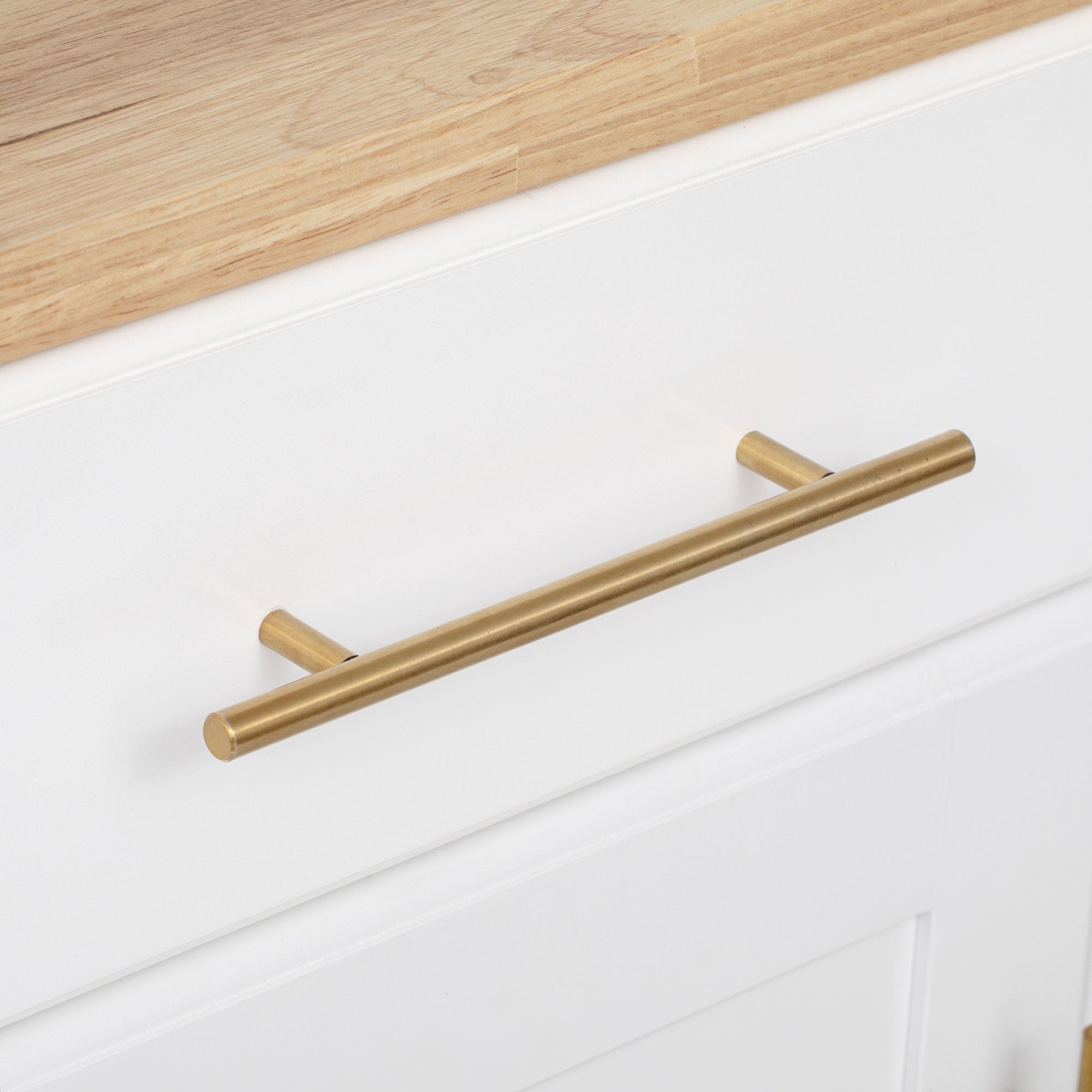 Honfleur rolling kitchen island gold drawer handle and wood countertop close-up in white finish on white background