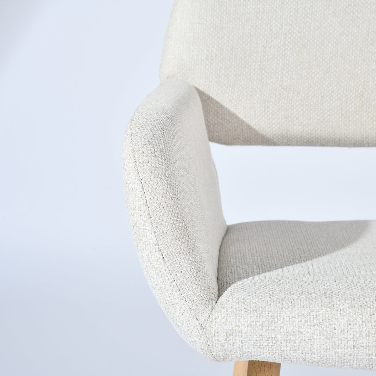 Mayfair beige fabric dining chair showing curved armrest and backrest detail