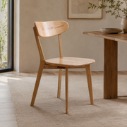 Mogan oak solid wood dining chair beside a wood dining table in a bright minimalist dining room