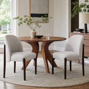 Orta gray upholstered barrel back dining chairs with solid rubberwood legs around a round dining table