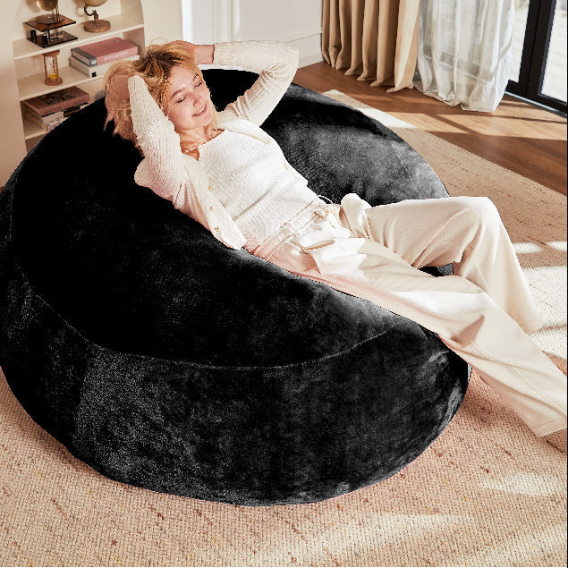 Pebble black bean bag chair showing a woman reclining comfortably in a neutral living room