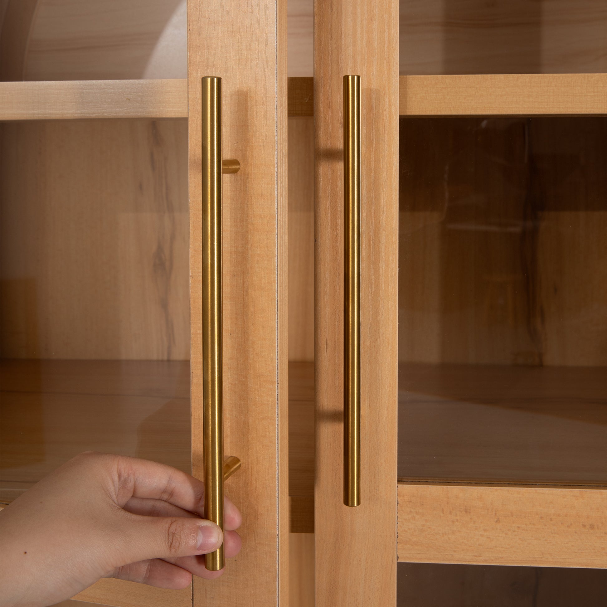 Savoy 71 inch natural wood pantry cabinet close-up of brushed gold handles on arched glass doors with wood grain finish