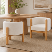 Soca white boucle upholstered dining armchairs with solid rubberwood post frame around a round dining table