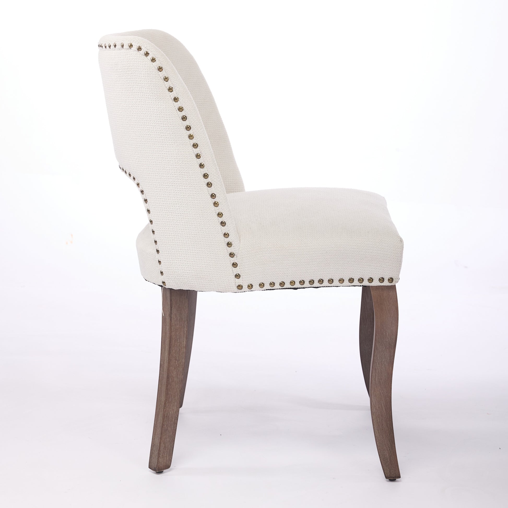 Tiberis beige dining chair showing the side profile with nailhead trim and curved backrest