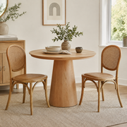 Vattern brown handwoven rattan cane dining chairs beside a round wood dining table