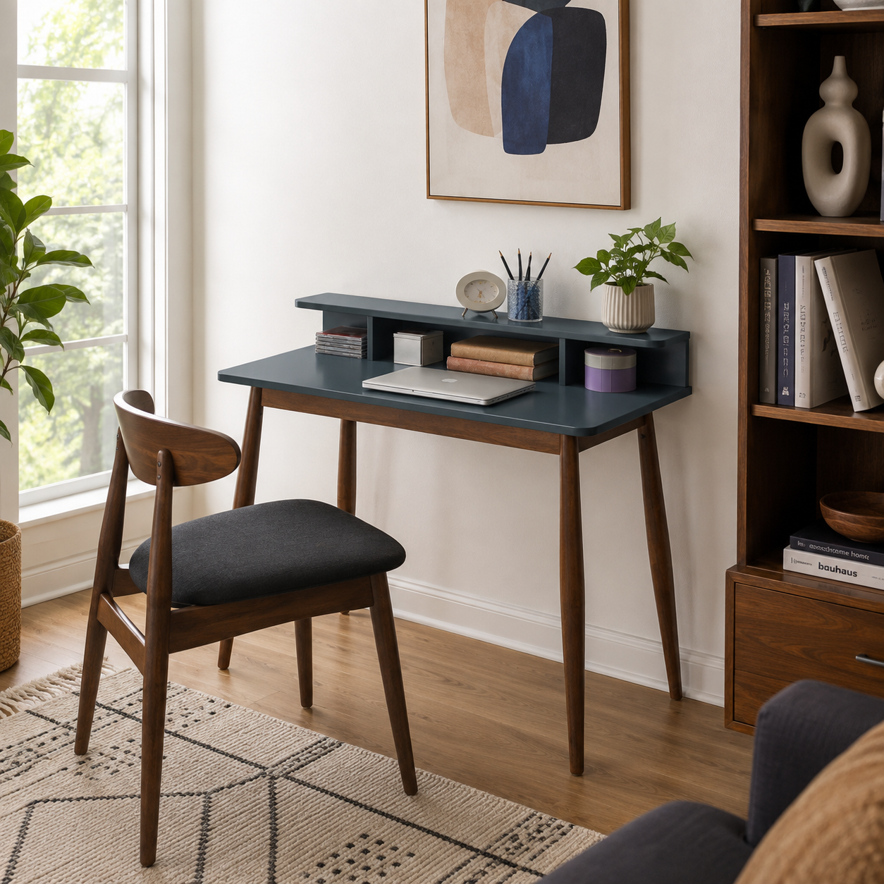 Visby grey writing desk showing a compact workspace with books and a black upholstered chair