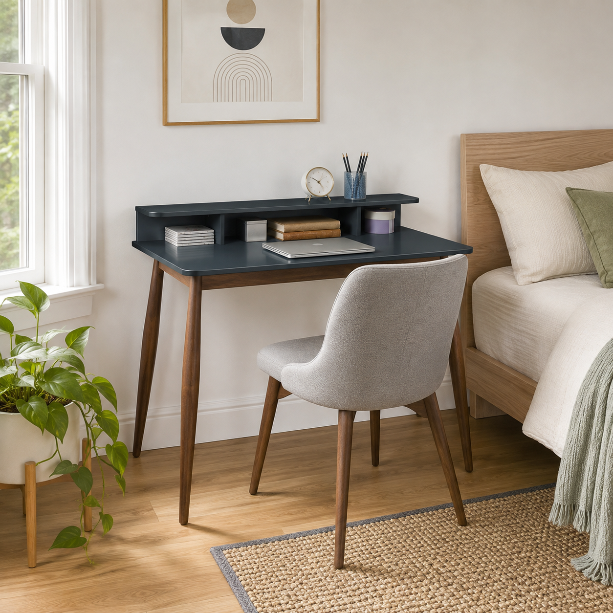 Visby grey writing desk showing a compact bedroom workspace with a white chair and greenery